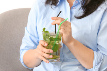 Woman drinking tasty cold ice tea at home