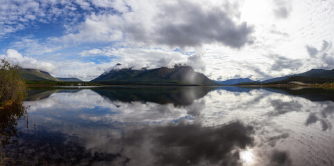 Panoramic View of Nares Lake with Mountains in the Background during a cloudy morning sunrise. Taken in Carcross, Yukon, Canada.