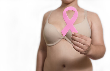 Latin woman holding pink ribbon in bra with a white background to use in October breast cancer awareness month BCAM