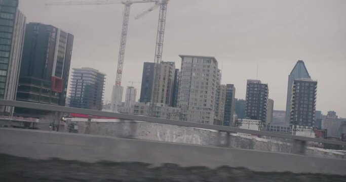 Montreal, Canada - November 15th 2017 : Modern skyscrapers buildings, construction cranes, Griffintown area filmed while driving on Quebec Autoroute 10.