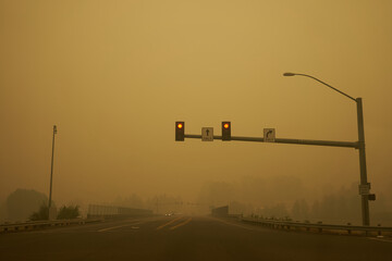 Traffic light on the road against fiery red sky with smokes from the Oregon wildfires in 2020. 