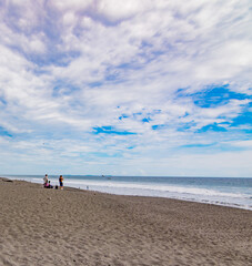 People enjoying La Barqueta beach, during a summer day with a partially cloudy sky. This is a sea turtle nesting site