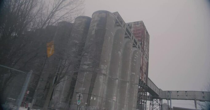 Montreal, Canada - November 15th 2017 : Dutch angle shot on concrete silos of Five Roses Flour ADM mill factory on the port, with cloudy sky in background.