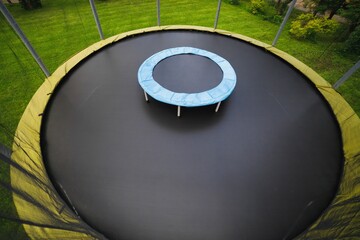 small trampoline on big round mat, size comparison, green lawn background
