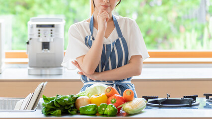 キッチンで考え事をする女性