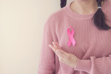 woman wearing pink top with pink ribbon, breast cancer awareness, October pink, World cancer day...