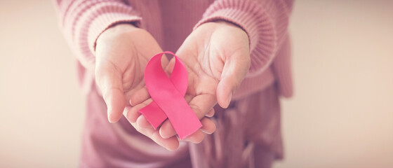 woman hands holding pink ribbon, breast cancer awareness, October pink, World cancer day concept