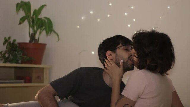 Young millenial couple in love kissing and smiling in the living room sharing a romantic moment