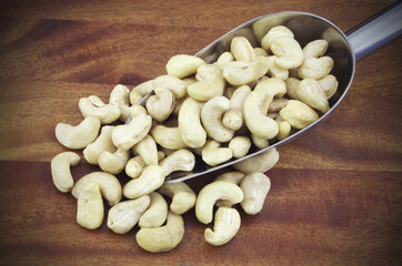 Cashew nuts with metallic scoop on wooden table