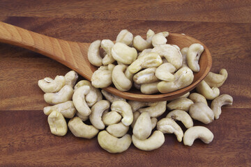 Cashew nuts with spoon on wooden table
