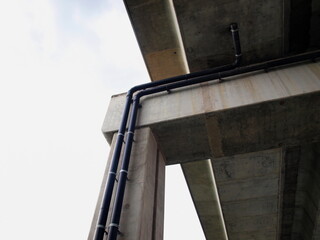 Drain pipes under a highway bridge. Black plastic pipes are installed on beams under bridge or overpass. For draining rainwater with a copy area. Focus close and choose the subject.