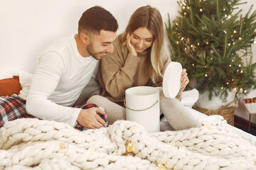 Couple sitting on a bed. Lady in a brown sweater. Woman with husband.
