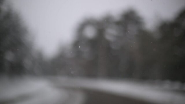 Slow motion snowy falling into the car, unfocus road at the background, road trip Spain
