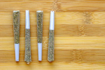 Several Legal Canadian Pre-Rolls Cannabis Joints on a wooden surface.