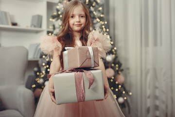 Fototapeta na wymiar Cute little girl in a pink dress. Child standing by the christmas tree