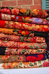 Kashmiri embroidered wool shawls folded in a stack. 
