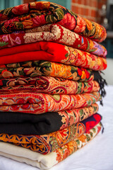 Kashmiri embroidered wool shawls folded in a stack. 