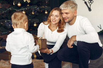 Mother in a white sweater. Family with christmas gifts. Child with parents in a christmas decorations.