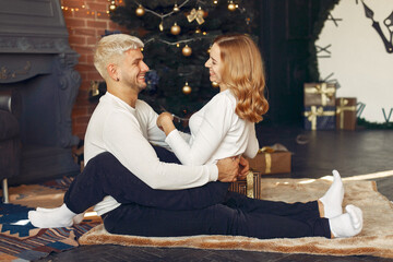 Couple near christmas tree. Lady in a white sweater. Family sitting on a floor.