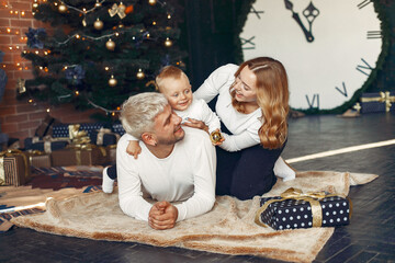 Mother in a white sweater. Family with christmas gifts. Child with parents in a christmas decorations.