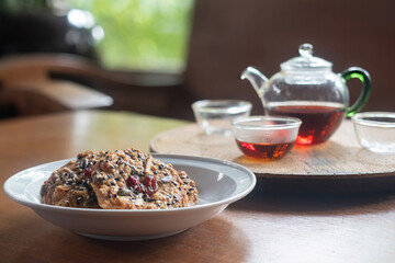 Homemade Whole grain Oatmeal Cookie with a background of  tea jug and cup of tea on wooden table