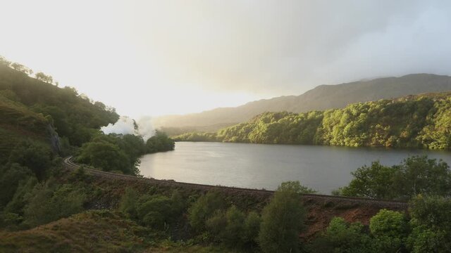 Jacobite Steam Train passing loch on West Highland Line between Mallaig and Fort William, Highlands, Scotland