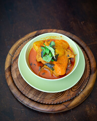 Chicken curry in a green bowl on a wooden base background.