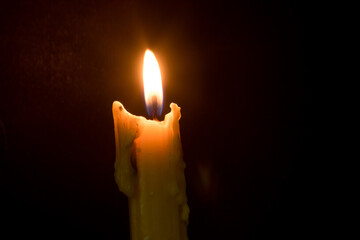 The candle was lit in a black religious background.