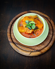 Chicken curry in a green bowl on a wooden base background.