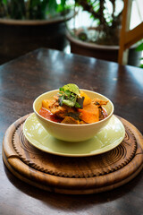 Chicken curry in a green bowl on a wooden base background.