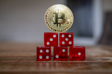  golden Bitcoin coin stands on a stack of red dice