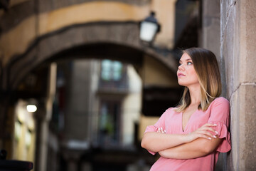 Fototapeta premium Young thoughtful woman near the stone wall in historical center of Barcelona