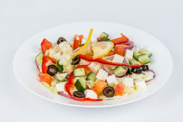 White, round plate with Greek salad on a white background