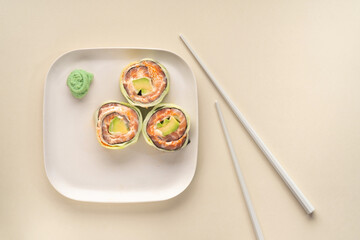 Healthy cucumber, salmon and avocado sushi roll with chopsticks. Vegetarian food, modern style