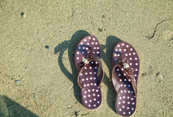 Naklejka premium Brown pair of sandals on the beach.