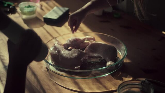 Child Sprinkles Salt On Chicken Legs At The Microwavable Glassware. - Wide Shot