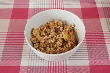 A bowl of whole grain muesli on a table with a red and white tablecloth