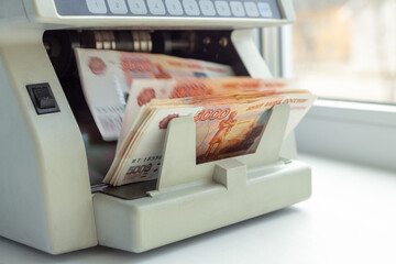Electronic money counter machine is counting russian ruble banknotes. Finance and business concept. Copy space