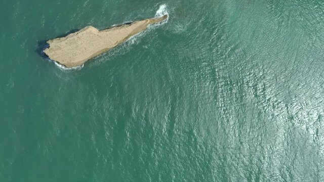 Aerial shot overlooking the rock el zapato in el morro, monte cristi waves pounding, blue water