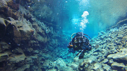 diver in drysuit swimming in icelandic glacial water