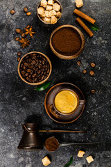 Creative flat lay with milled coffee, coffee beans, brown sugar and espresso on dark rustic background