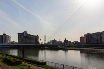 Obraz premium 都市の河川と飛行機雲が交差している空