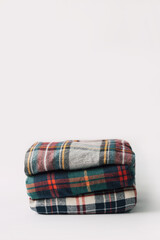 Stack of colorful checkered clothing for fall or winter cold weather on white background with copy space. 