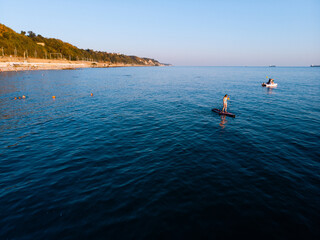 Attractive Woman on Stand Up Paddle Board, Woman paddling on sup board and enjoying turquoise transparent water. Tropical travel, wanderlust and water activity concept. Sunset and relax