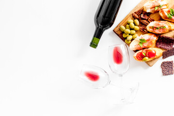 Wine appetizer. Toasts, nuts, olives on white desk top view copy space