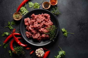 Minced beef. Ground meat with ingredients for cooking on black background