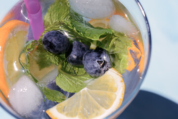 Homemade lemonade with blueberries, lemon wedges and mint leaves with ice cubes, top view, macro