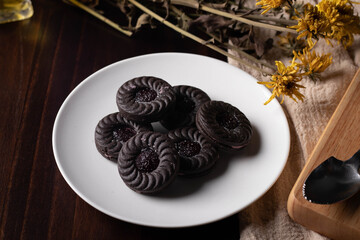 Chocolate cookies in a white plate on a dark wooden background.