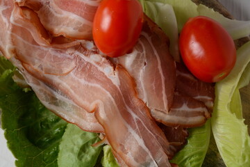 Raw bacon slices on lettuce leaves