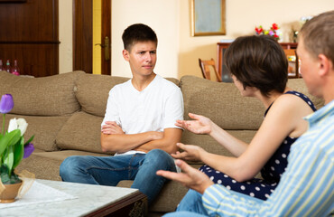 Angry parents quarrelling with his upset teenage son at home interior
